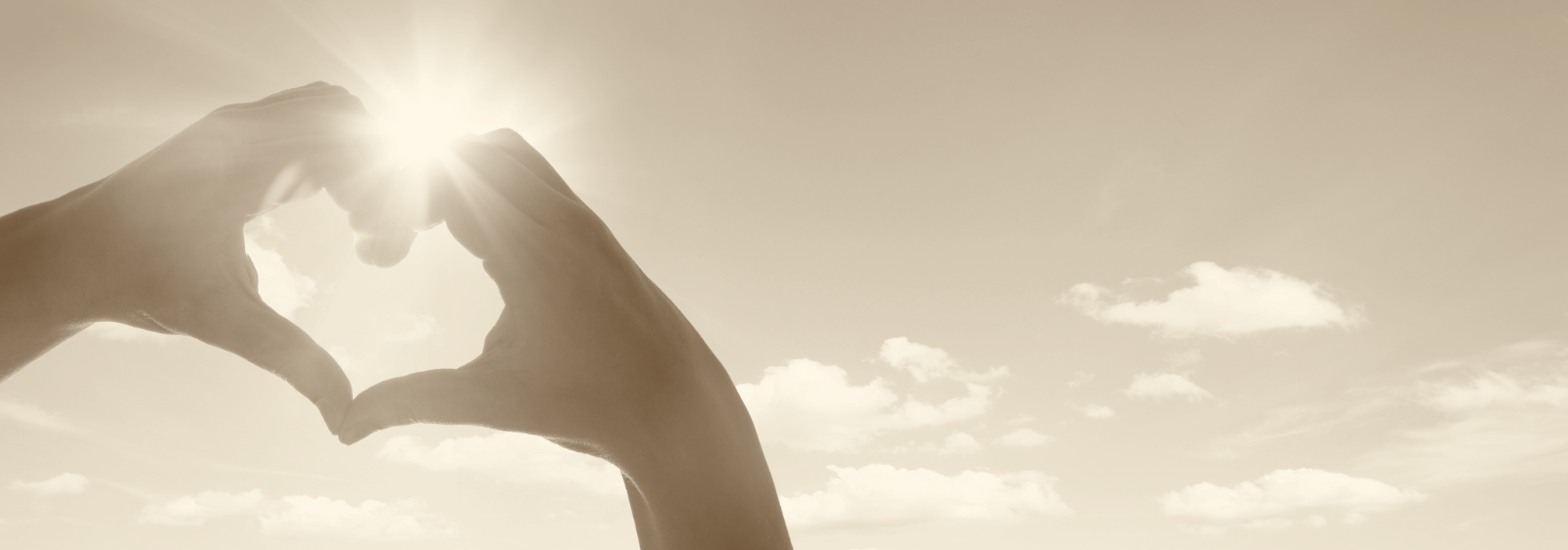 Herzform aus zwei Händen vor der Sonne als Sinnbild für Vertrauen, Empathie und ganzheitliche Begleitung